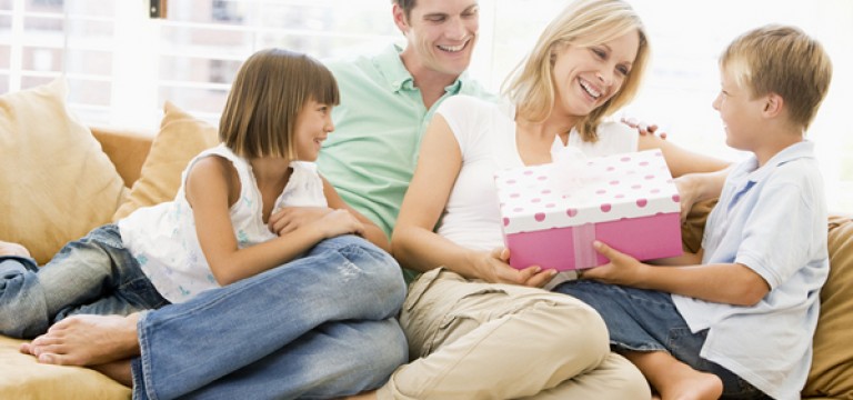 Family in living room with mother receiving gift and smiling